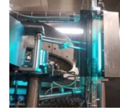 The UV-C fixture mounted on the bottling machinery, lamps lit