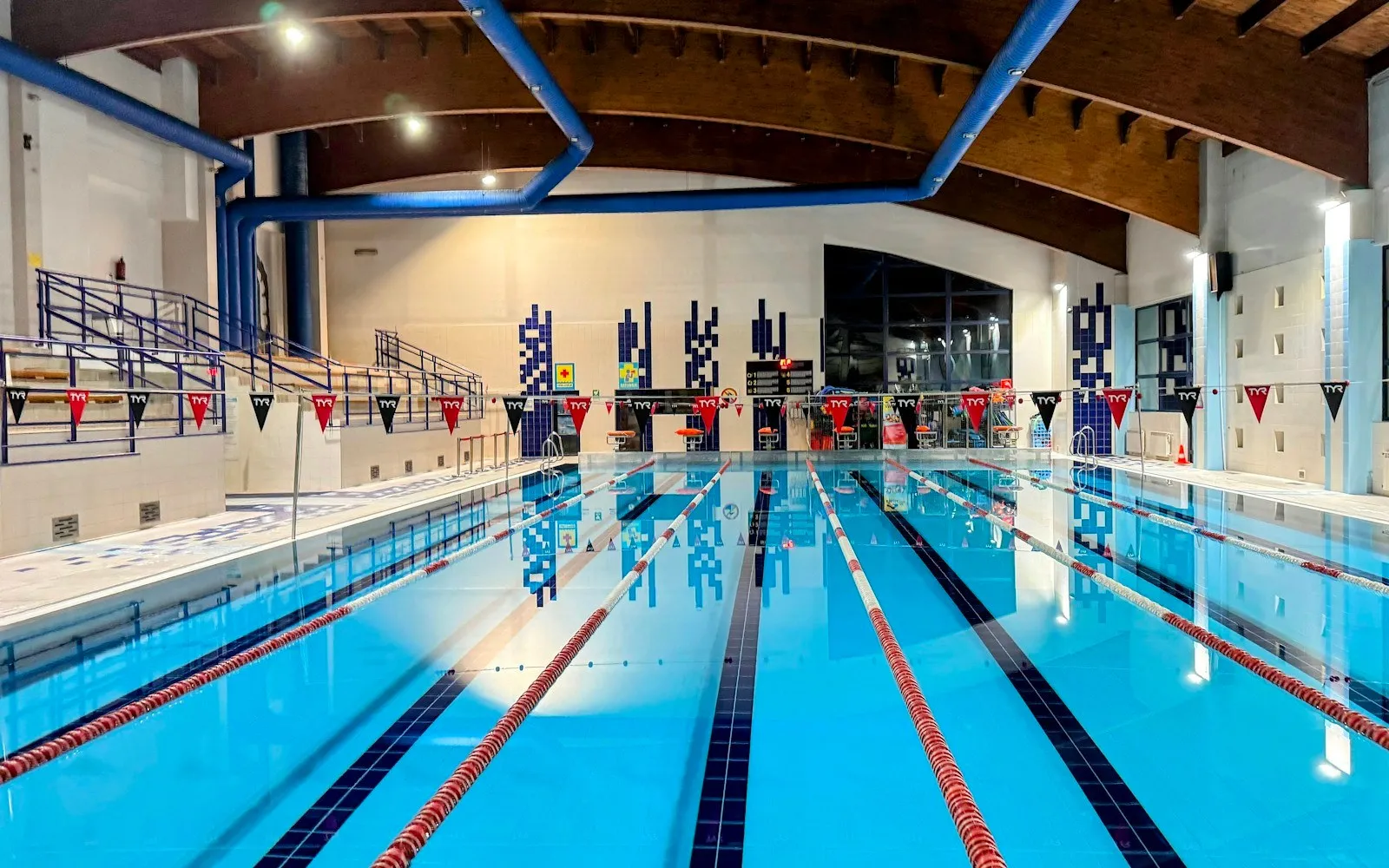 An indoor competition pool with lane ropes under a timber roof