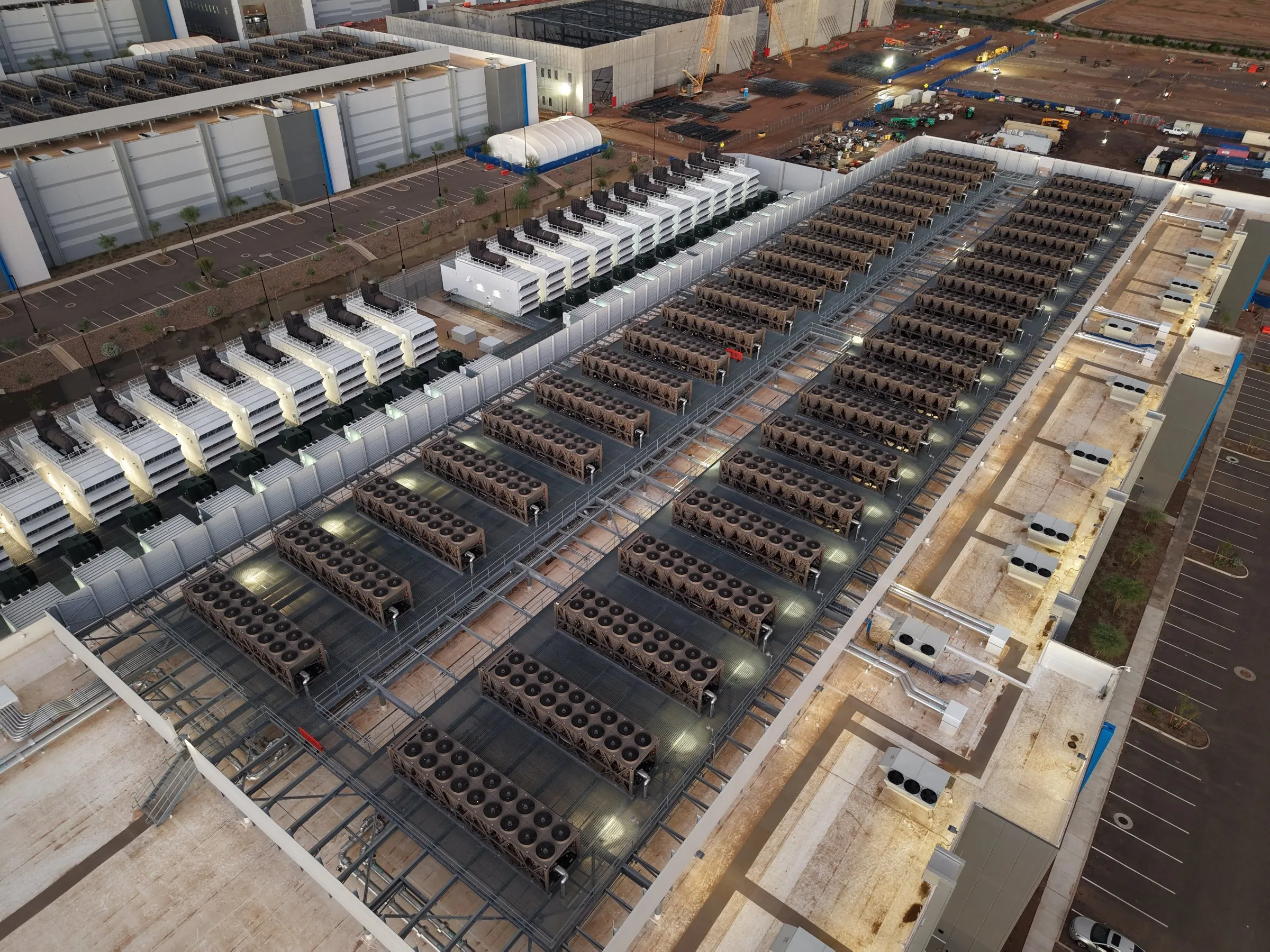 Rows of chillers and backup generators on the roof of a data center at dusk