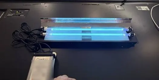 A FreshFilter-ME lamp assembly lit on a workbench beside its Cognituv power supply