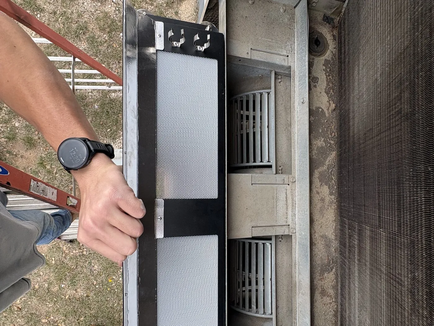 A technician sliding a Cognituv FreshFilter-ME into a wall-mounted HVAC unit