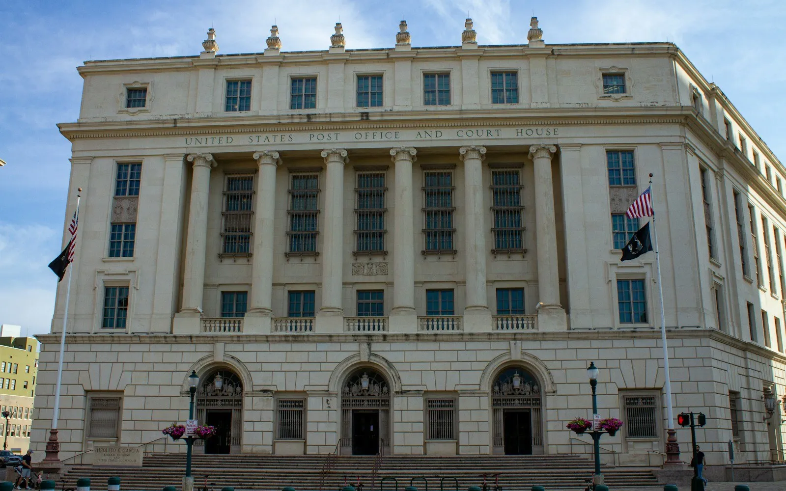 A stone civic building with columns and an American flag