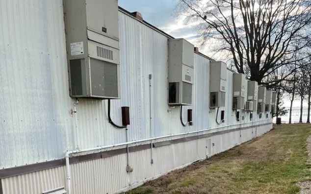 A row of modular buildings with wall-mounted Bard HVAC units along one side
