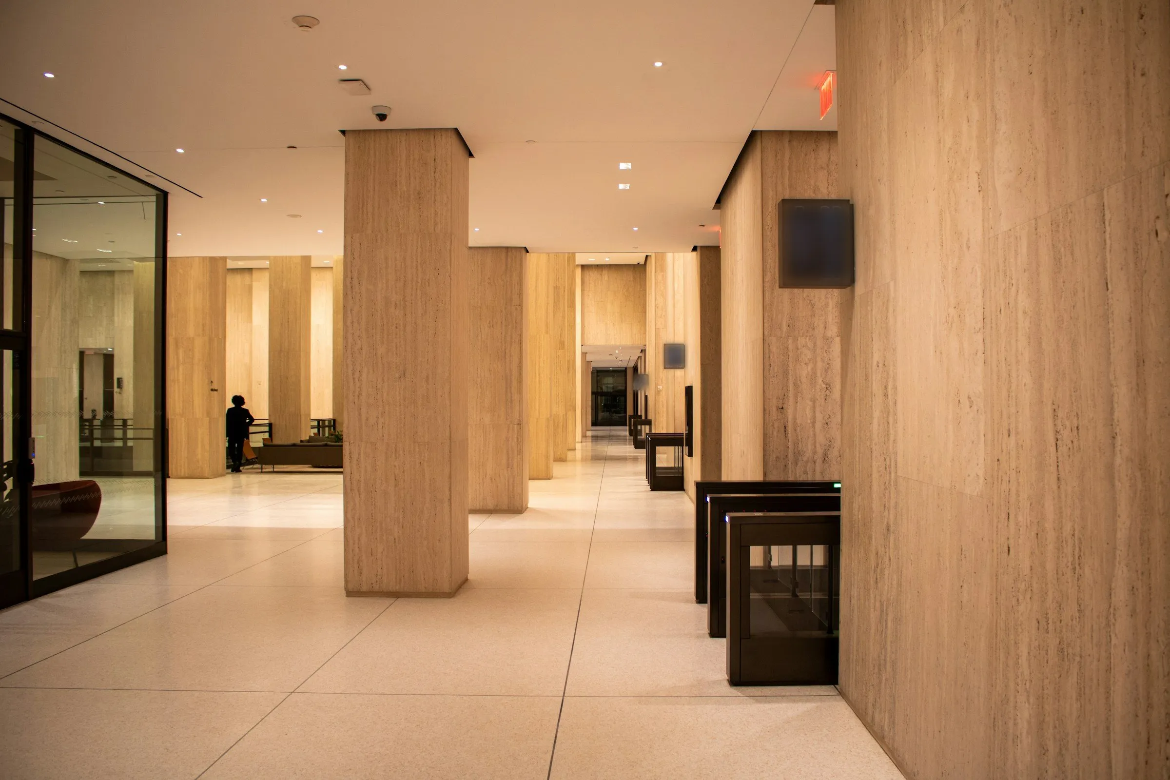An office tower lobby with stone columns and security turnstiles