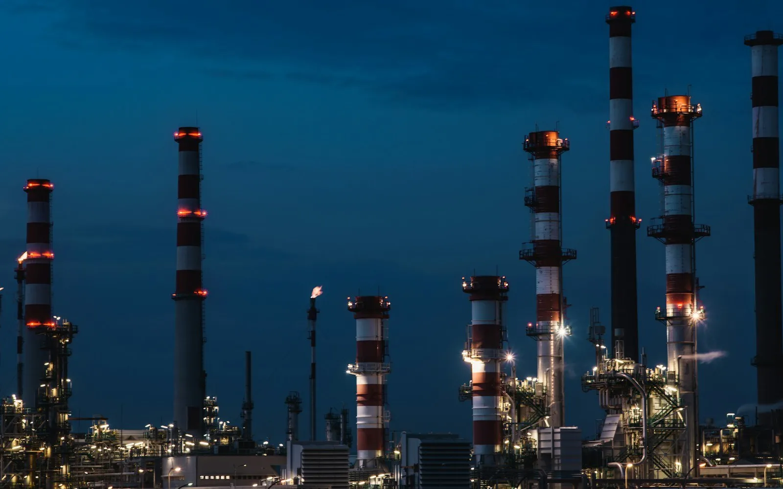 Refinery stacks and towers lit at dusk