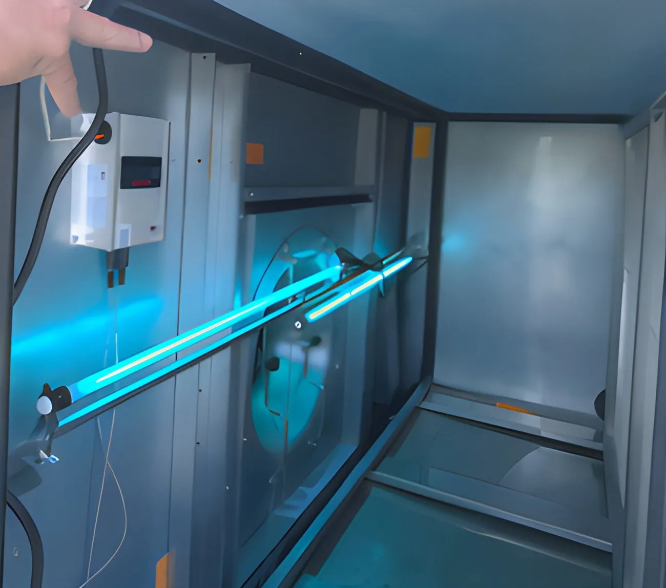 UV-C lamps lit inside an air handler, a hand on the cabinet door