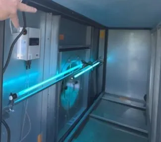 Cognituv Grid UV-C lamps lit inside an air handler, a hand on the cabinet door